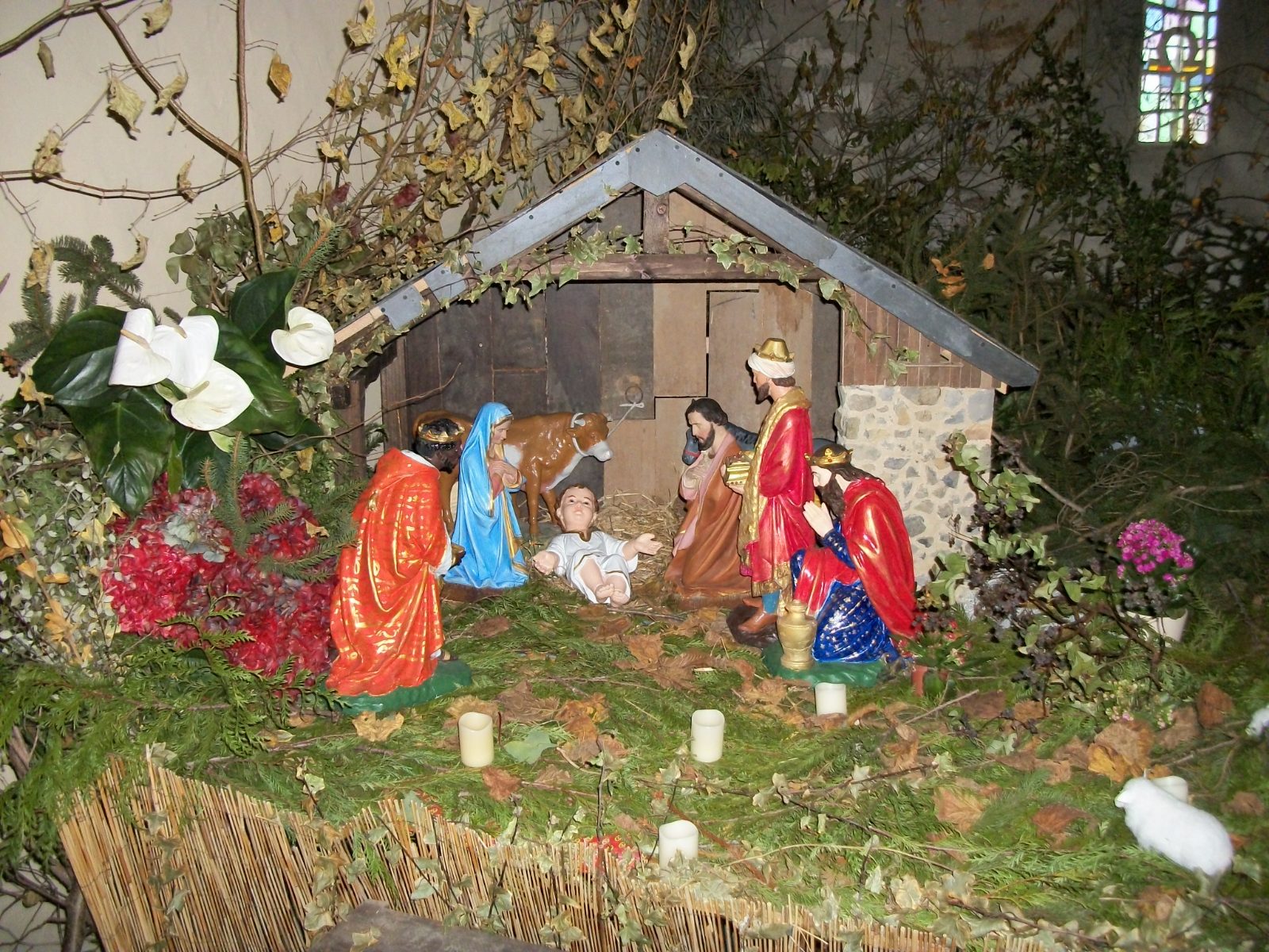A simple, bright nativity scene: a wooden stable, the Holy Family and a few figures